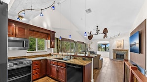A modern kitchen with built-in appliances, wooden cabinetry, and a large island. - 601 Monroe Ave (Cape Canaveral)
