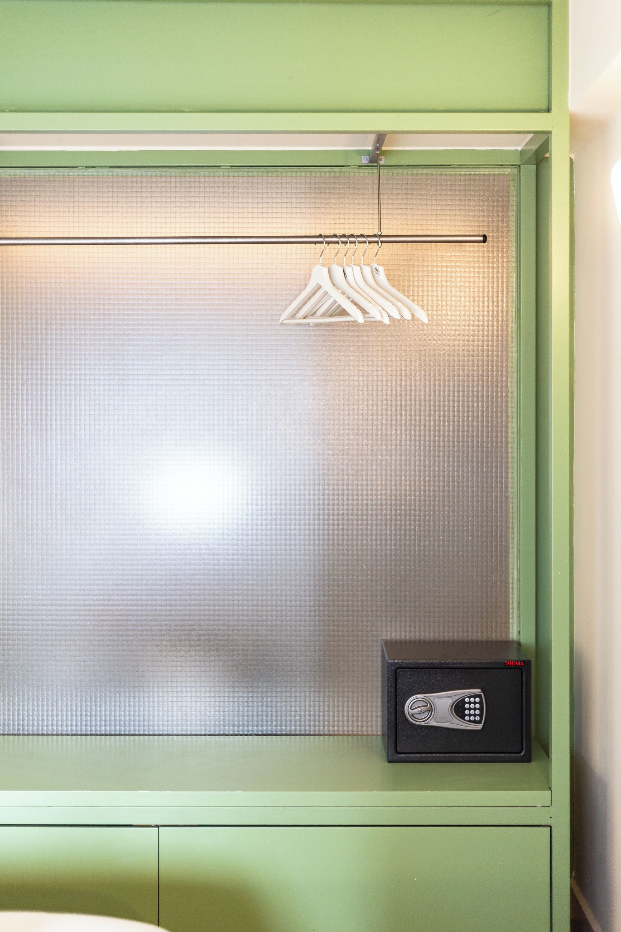 A green cabinet with a metal mesh window, a clothes rack, and a black safe.