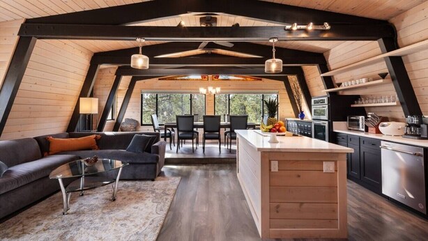 A modern loft-style interior with a dining area, kitchen, and living space. - Tahoe Sanctuary | Hot Tub Sauna | Mountain & Lake Views | Air Conditioning (South Lake Tahoe)