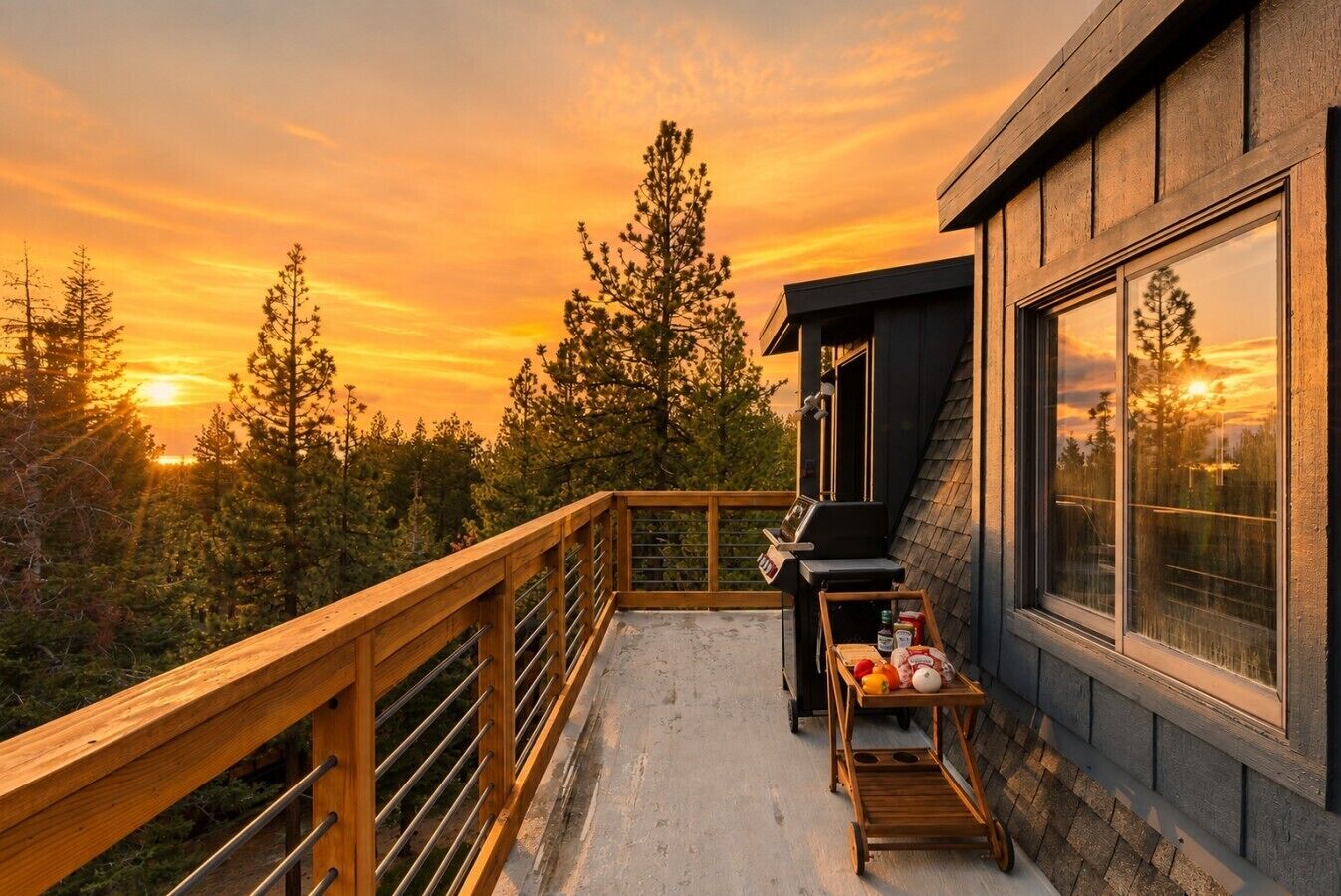 A balcony with a view of a sunset, a grill, and a table with food items.