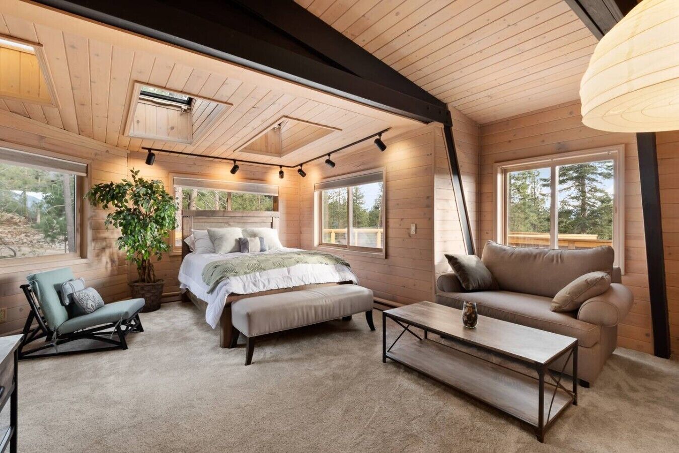 Ein gemütliches Schlafzimmer mit Bett, Nachttischen, einer Couch und einem großen Fenster.