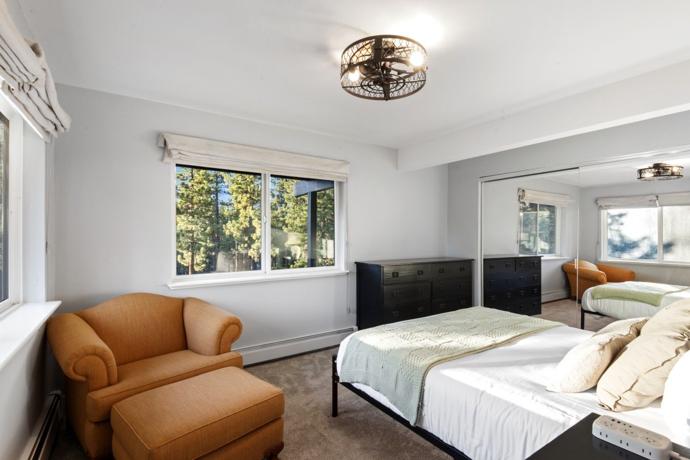 A bedroom with a bed, a chair, a dresser, and a mirror.