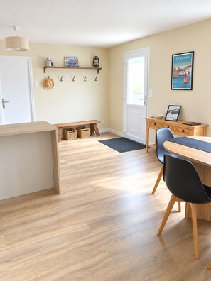 Una cocina moderna con suelo de madera, una banca empotrada y una zona de comedor con mesa y sillas.