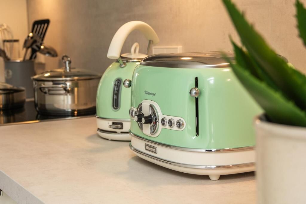 Duas torradeiras de estilo antigo em uma bancada de cozinha, com um vaso de planta em primeiro plano.