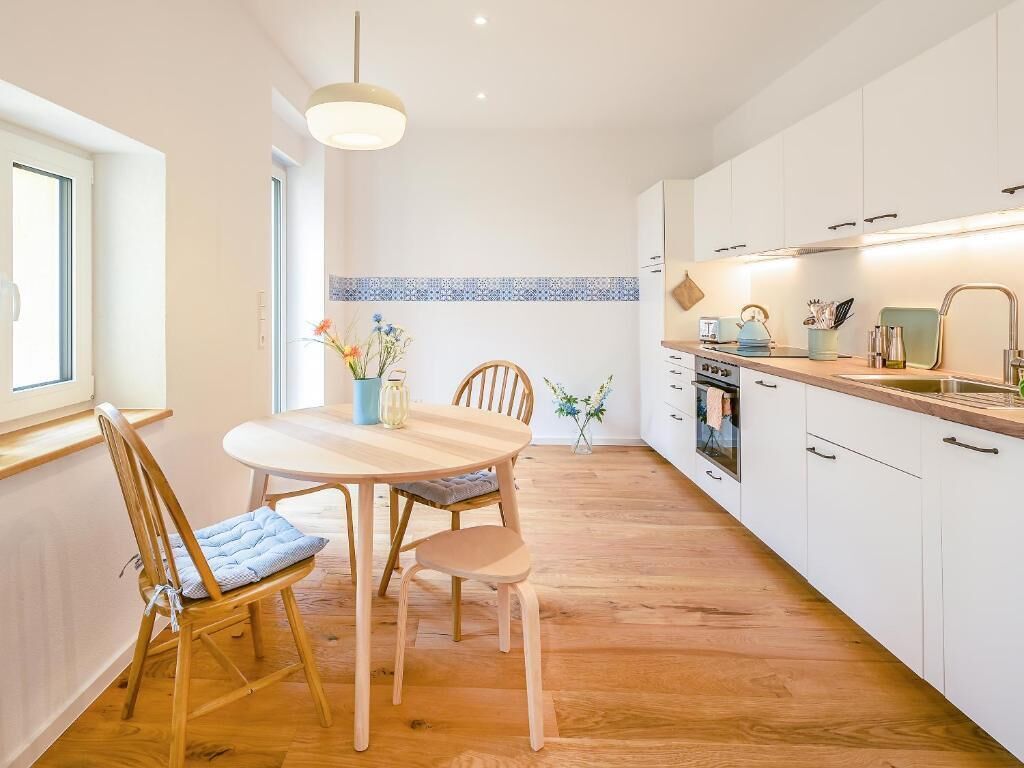 A modern kitchen with white cabinets, a wooden dining table, and chairs.