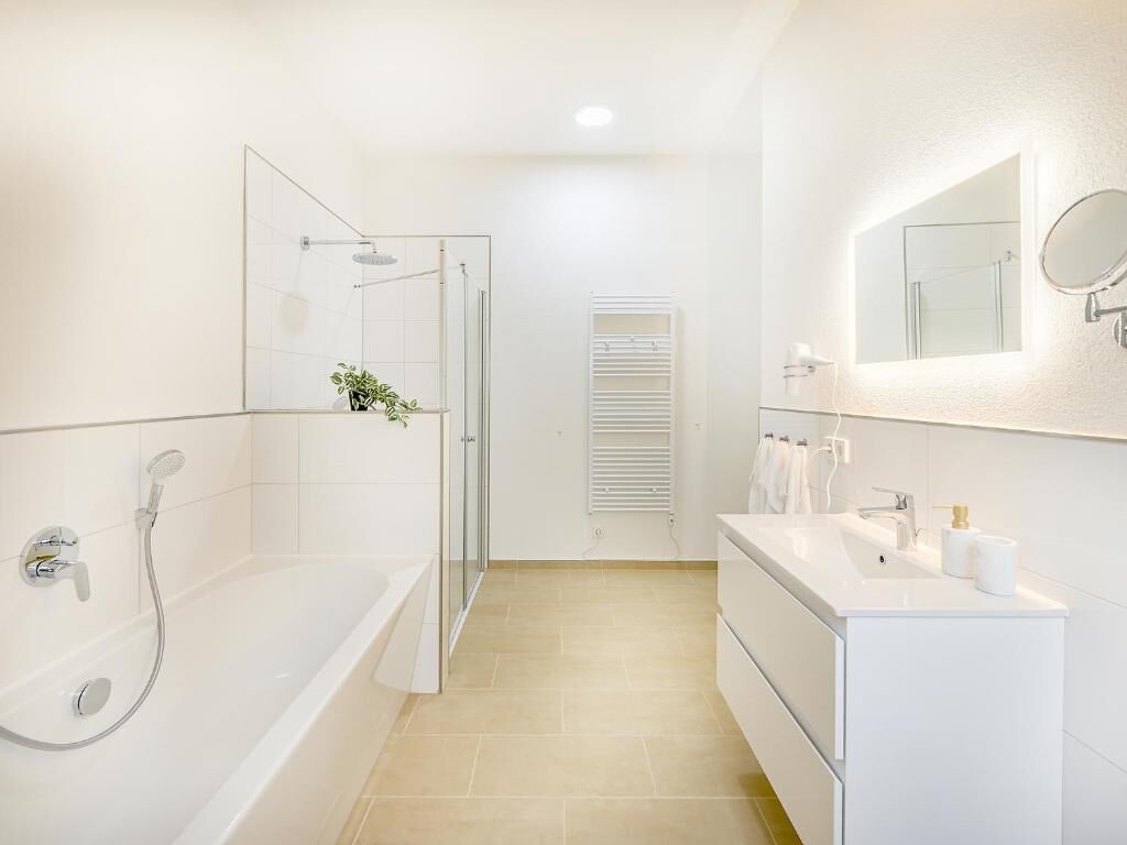 A modern bathroom with a glass-enclosed shower, a white vanity with a mirror, and a towel rack.