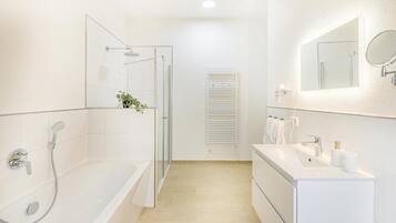 A modern bathroom with a glass-enclosed shower, a white vanity with a mirror, and a towel rack.