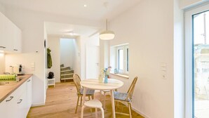 Una cocina moderna con suelo de madera, una mesa de comedor con sillas y un gran ventanal que proporciona luz natural.