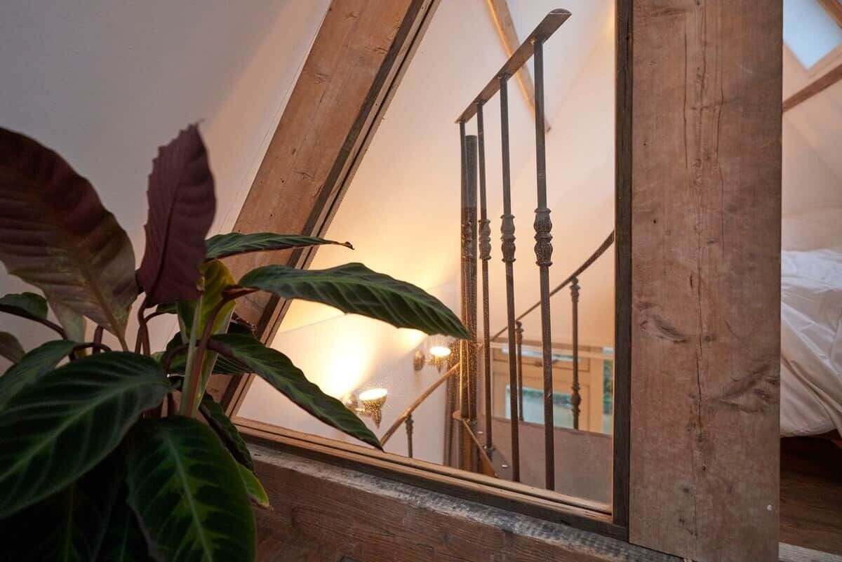 Un miroir à cadre en bois qui reflète un escalier et une zone de piscine.