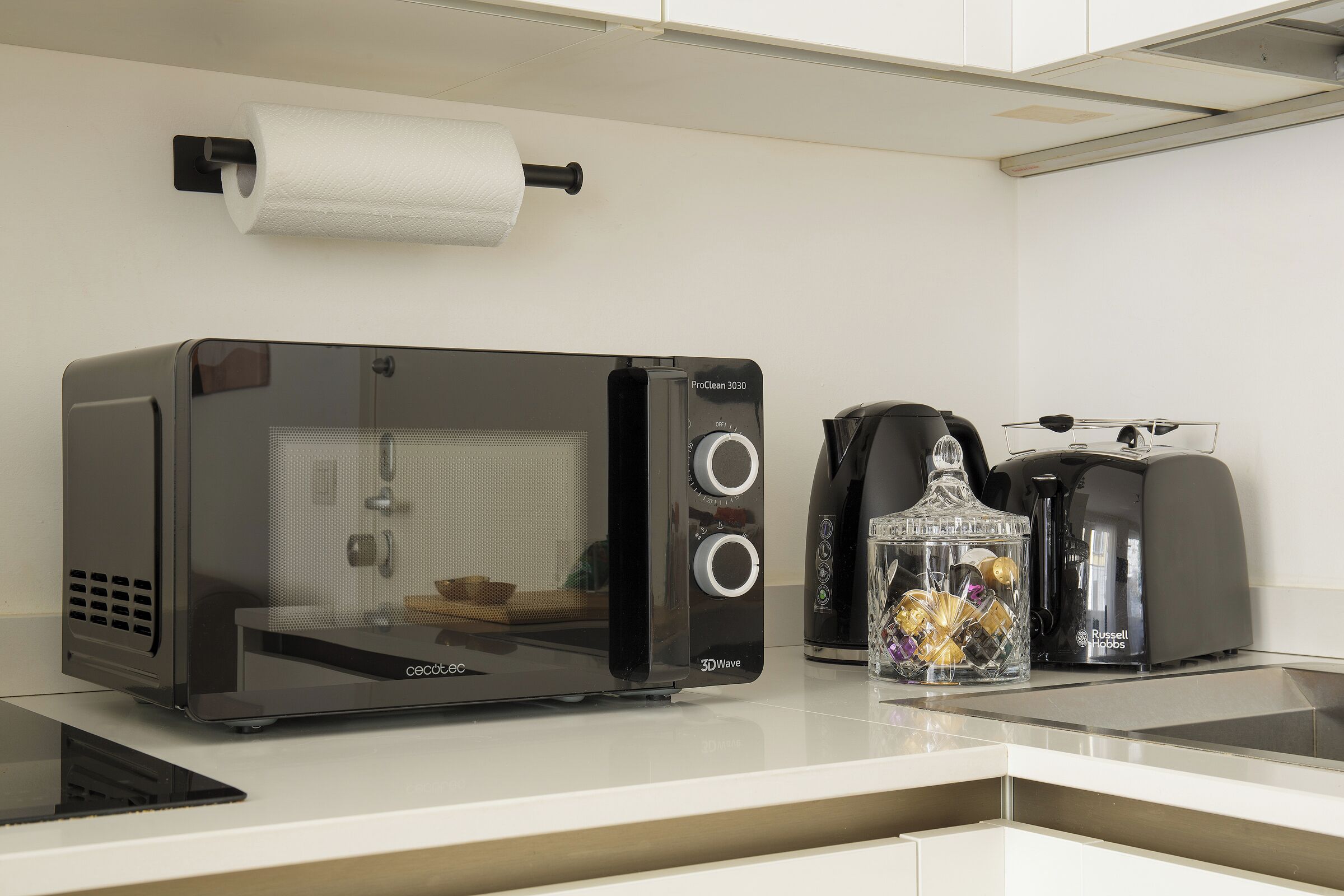 Una zona cottura accessoriata con un forno tostapane 3DWave, una macchina da caffè e un vasetto di vetro con decorazioni.