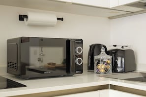 A kitchenette with a 3DWave toaster oven, a coffee maker, and a glass jar with decorative items.