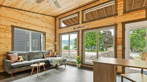 Ein gemütliches Zimmer mit einer Couch, einem kleinen Tisch und großen Fenstern mit Blick ins Freie.
