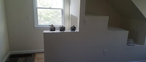 A room with a window, a white wall, and a wooden floor.