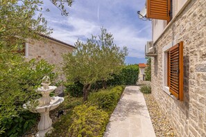 A narrow stone pathway flanked by greenery and a stone building with wooden shutters. - Villa OASA with private heated pool (Ljutići)
