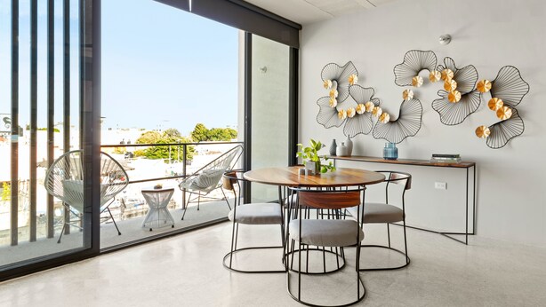 Ein moderner Essbereich mit einem runden Tisch, Stühlen und einem Balkon mit Blick.