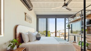 Ein modernes Schlafzimmer mit Bett, Nachttisch und Blick durch große Fenster.