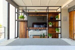 A modern living room with a sofa, a TV, wooden shelves, and potted plants. - Ocean Boutique Condos (Playa del Carmen)