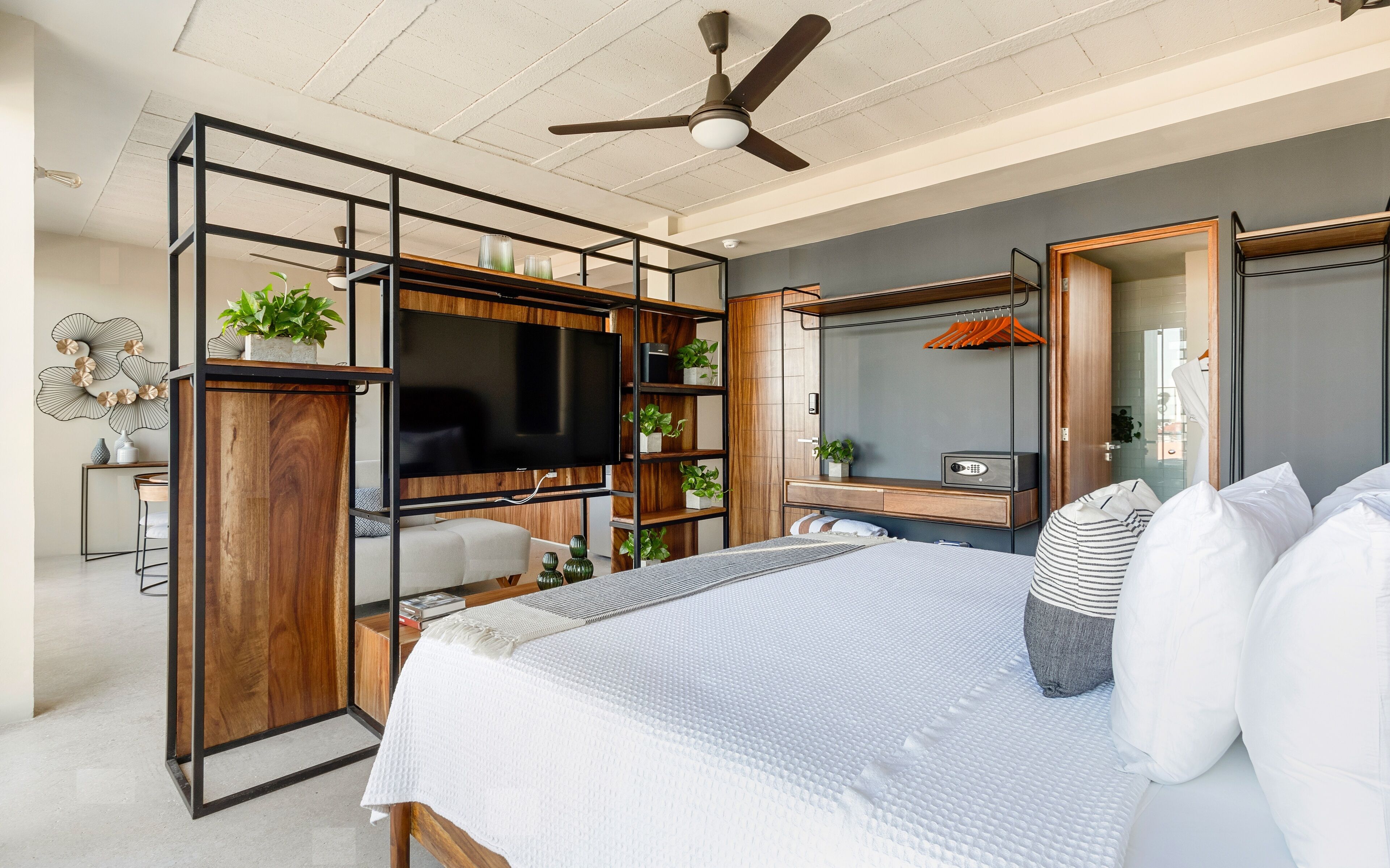 A modern bedroom with a bed, a TV, a wardrobe, and a desk area.