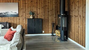 Un salon avec un canapé, une cheminée et des lambris en bois sur les murs.