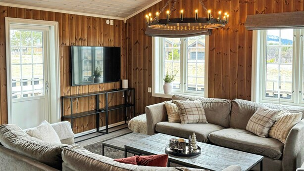 Un salon chaleureux avec des murs en bois, un téléviseur à écran plat, un ensemble de canapés et une table basse.