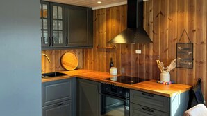Une cuisine moderne avec un lambris en bois, un four encastré et un coin repas doté de chaises en cuir.
