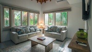 A living room with two sofas, a coffee table, and a TV. - Tranquil Jungle Nest Near Guiones Surf with Pool (Guanacaste Province)