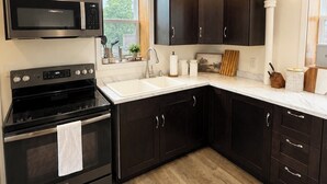 Una cocina moderna con armarios oscuros, una estufa de acero inoxidable y un microondas.