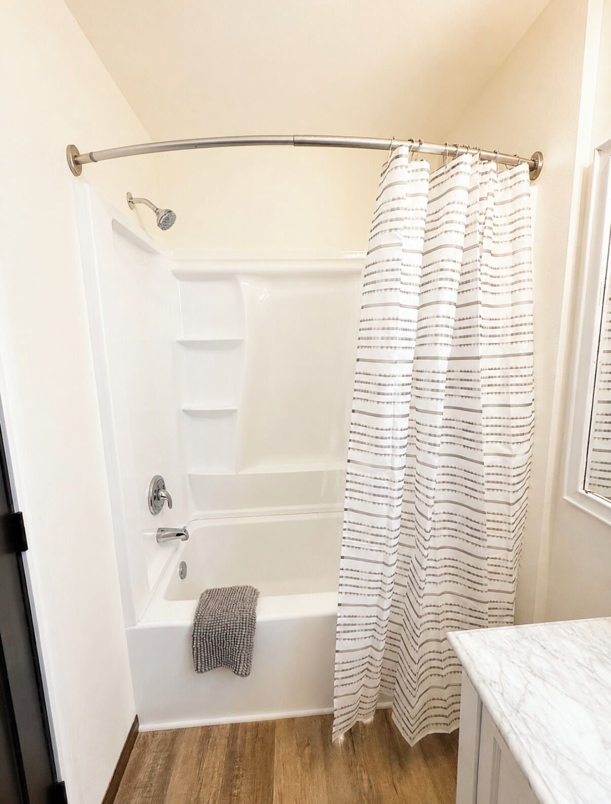 A bathroom with a bathtub, a shower curtain, and a towel.