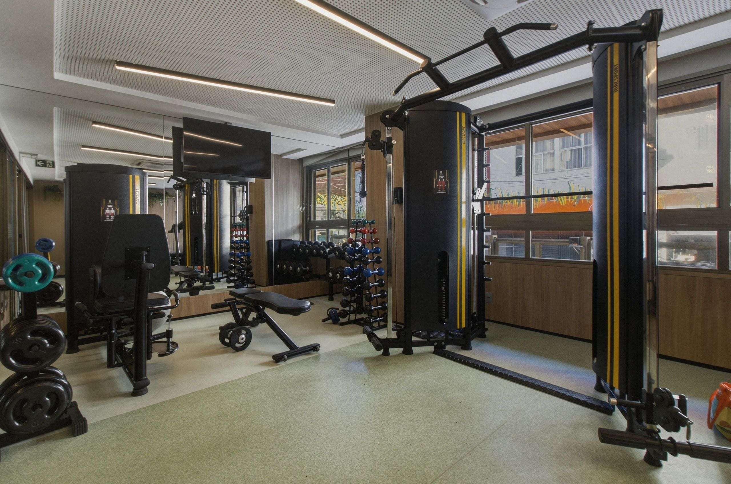 A gym with various exercise equipment, a bench, and dumbbells.