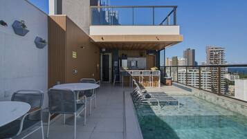 Um terraço no telhado com piscina, área de estar externa e vista para o horizonte da cidade.