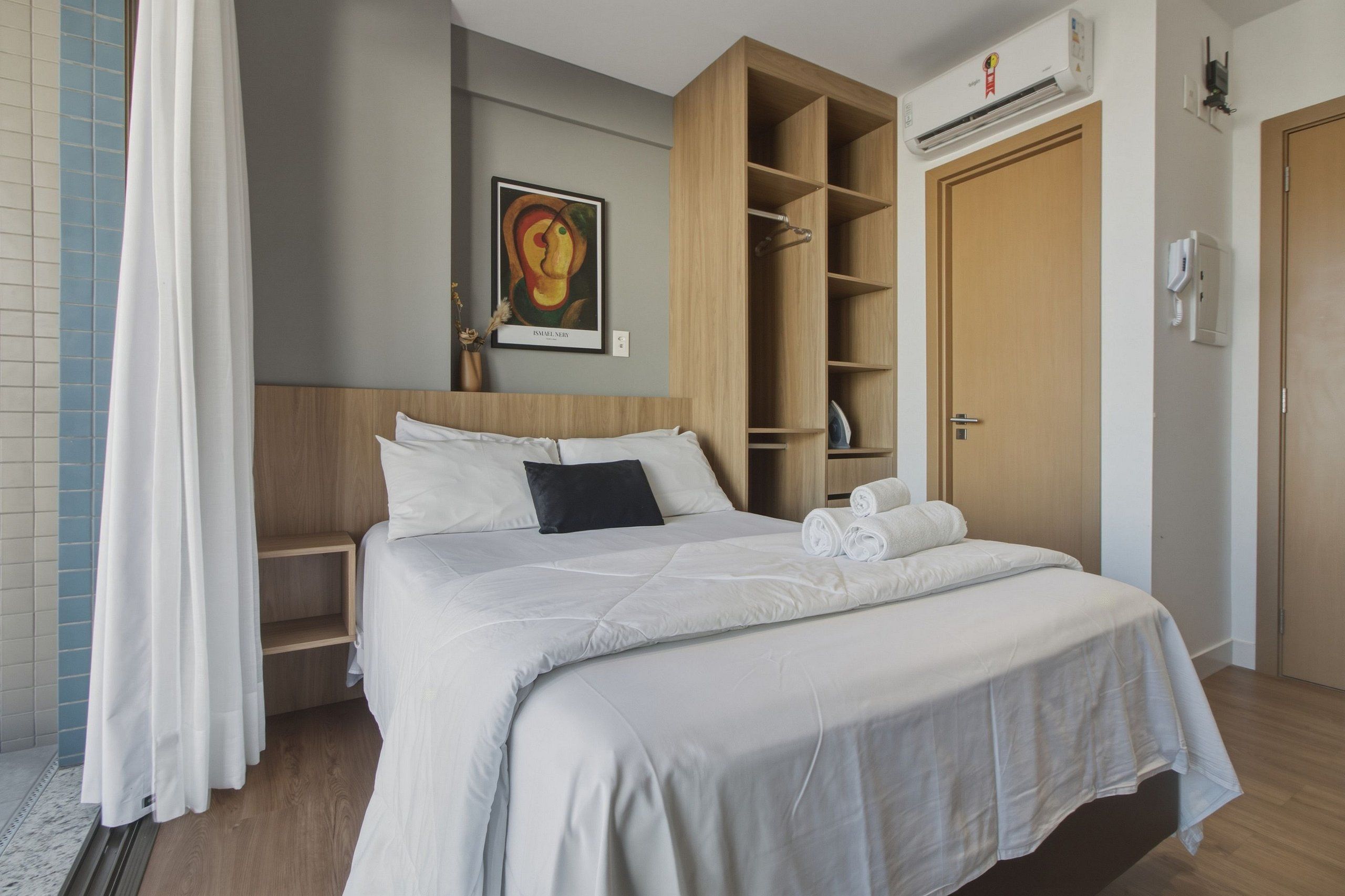 Ein Hotelzimmer mit Bett, Kleiderschrank, einem Bild an der Wand und einer Klimaanlage.