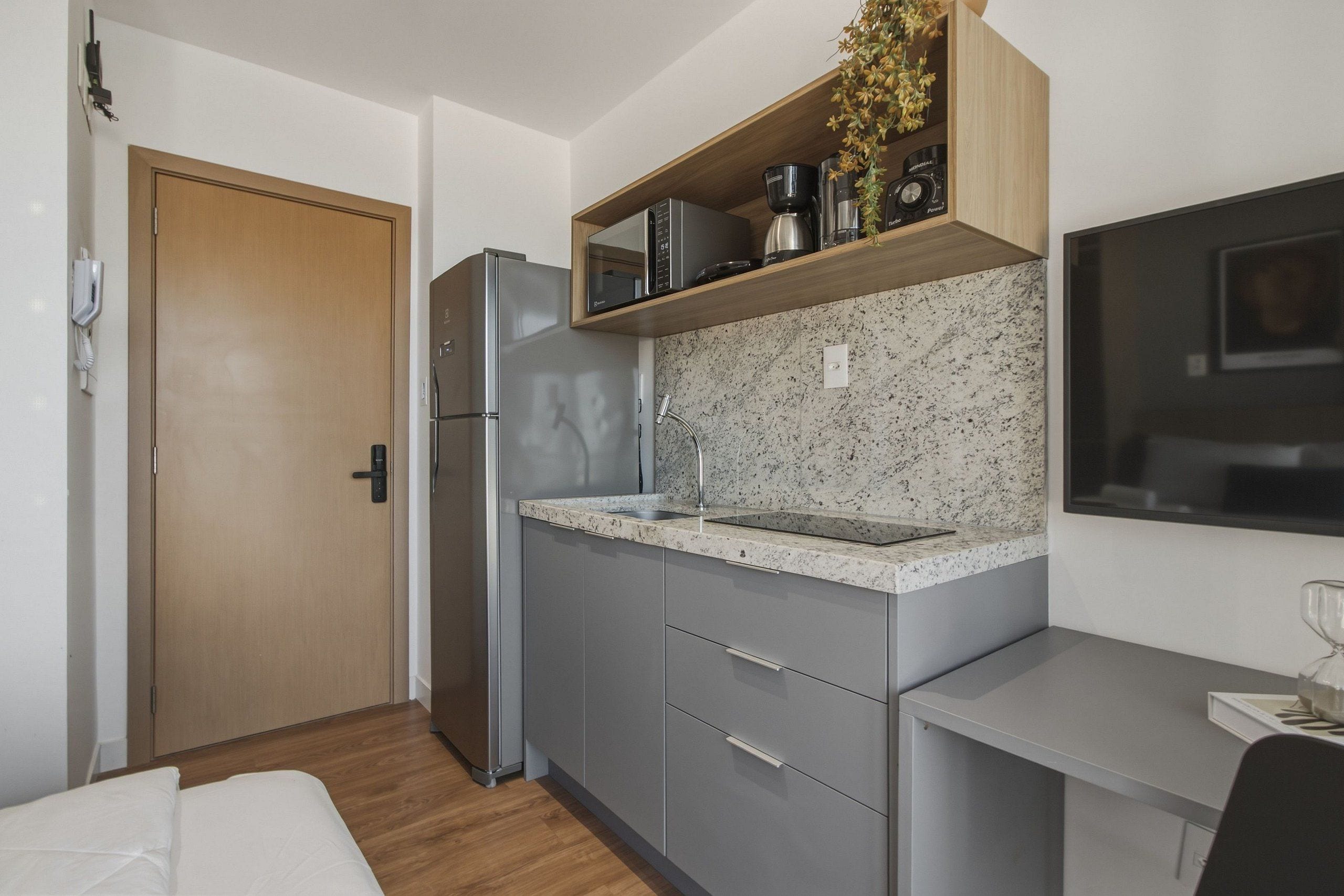 Eine kompakte Küche mit Kühlschrank, Mikrowelle und einer Arbeitsfläche mit Spüle.