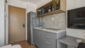 Uma cozinha compacta com geladeira, micro-ondas e bancada com pia.