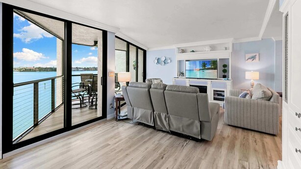 Una sala de estar moderna con un sofá, un televisor y un comedor con vistas al agua.