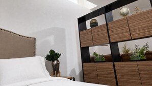 Ein Schlafzimmer mit einem Bett, einem Nachttisch, einer Kommode mit Globus und einem Oberlicht.