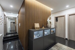 A modern reception area with a wooden panel wall, a reception desk with glass display cases, and a carpeted floor. - Doce como Laranja @ Boavista Executive Studios (Porto)