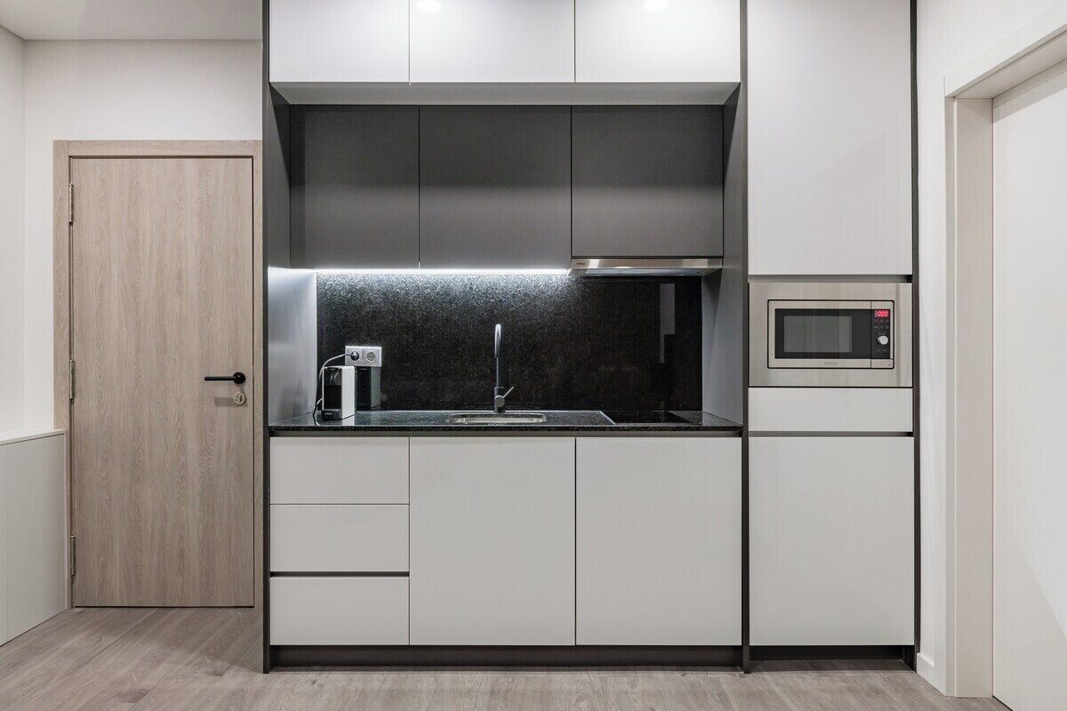 A compact kitchen with a microwave, a coffee maker, and a built-in oven.