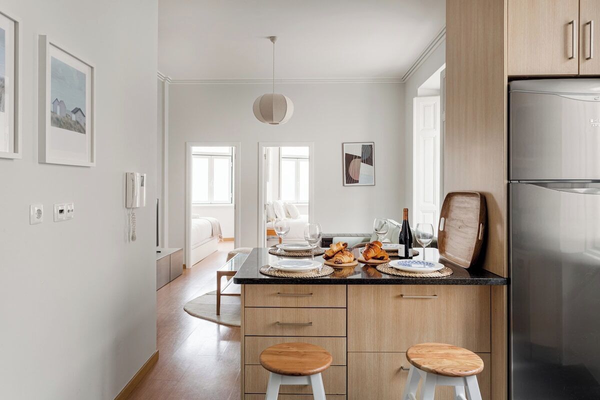 A modern kitchen with wooden cabinets, a stainless steel refrigerator, and a dining area with a table set for two.