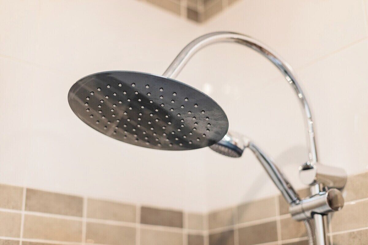 A showerhead with a perforated design, mounted on a chrome fixture.