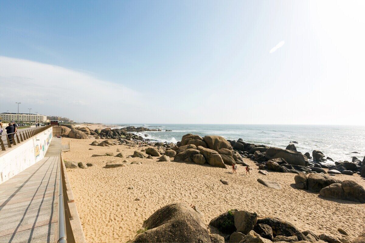 A beach with a walkway, large rocks, and the ocean.