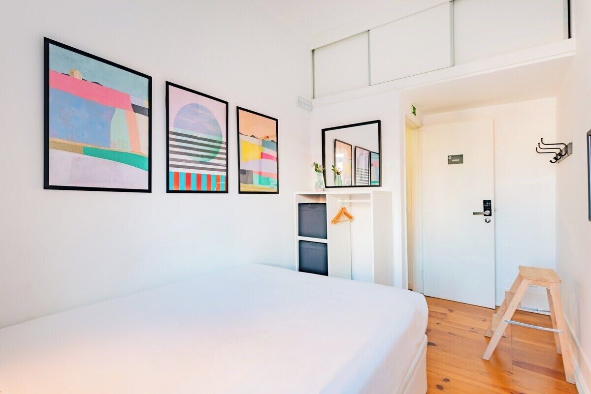 Une chambre à coucher avec un lit, une armoire, une porte et des œuvres d’art accrochées au mur.