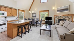 Una cocina amplia con una isla central, comedor con sillas, chimenea y sala de estar con sofá.