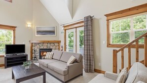 Una sala de estar con chimenea, un sofá, una mesa de centro y un televisor.