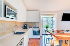 A compact kitchen with a microwave, oven, sink, and a dining area with stools. - Double Room @ Guest Inn 2 Boutique House (campo pequeno)