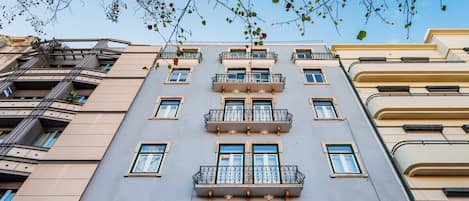 A multi-story building with balconies, large windows, and a clear sky.