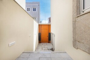 A narrow hallway with a wooden door, a radiator, and a window on the right wall. - Matosinhos Seaside Cozy Studio (Matosinhos)