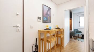 Un pasillo con una mesa y sillas de madera, un cartel en la pared y una puerta con manija.