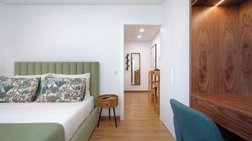 Un dormitorio moderno con un cabecero tapizado en verde, un aparador de madera y una silla color turquesa.