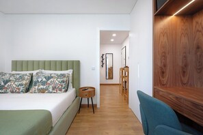 A modern bedroom with a green upholstered headboard, a wooden sideboard, and a teal chair. - Matosinhos Seaside Cozy Studio (Matosinhos)