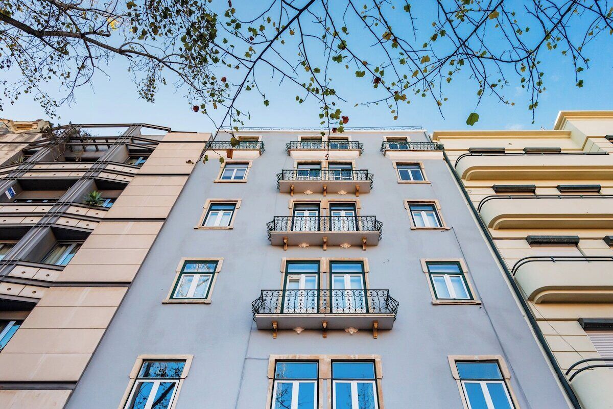 A multi-story building with balconies, large windows, and a clear sky.